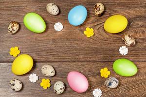 Frame of multicolored Easter eggs on a brown wooden background