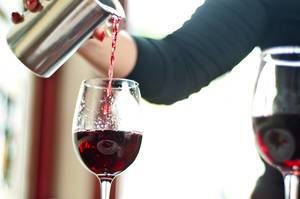 Frau gießt Rotwein in ein Glas