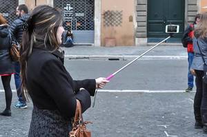 Frau hält ein Smartphone auf einem Selfiestick