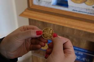 Frau hält eine goldene Münze in den Händen, die sie als Souvenir im Schloss Slavkov in Austerlitz gekauft hat