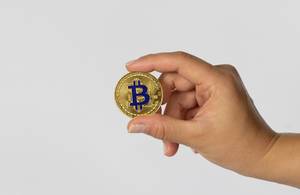 Frau hält einen goldenen Bitcoin