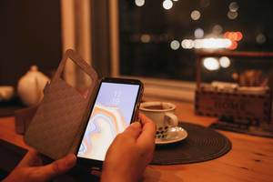 Frau hält Smartphone mit Bokeh Hintergrund in einem Café
