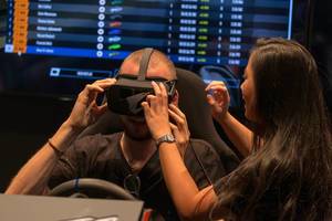 Frau hilft Mann beim Testen der Virtual Reality-Brille von AORUS