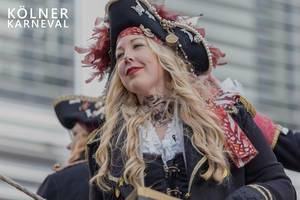 Frau im Kostüm als Piratenbraut verkleidet, fährt auf einem Festwagen beim Rosenmontagsumzug mit, neben dem Bildtitel "Kölner Karneval"