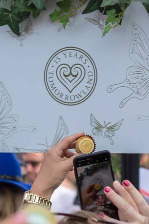 Frau macht Foto von Cupcake zum 15-jährigen Jubliäum vor Schild "15 years Tomorrowland"