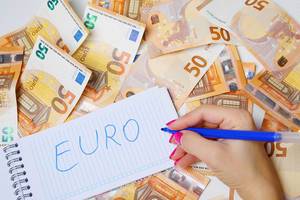 Frau schreiben "Euro" auf einen Zettel zwischen 50-Euro-Geldscheinen