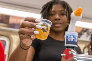 Frau serviert Bier aus Chicagos Handwerksbrauerei Goose Island in Plastikbecher mit dem Logo der Company