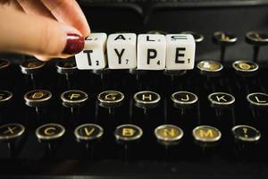 Frauenhand vervollständigt das Wort "Type" mit Hilfe von Buchstabenwürfeln