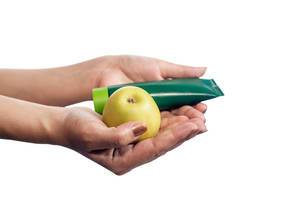 Frauenhände halten pflegende Handcreme und knackigen grünen Apfel vor weißem Hintergrund