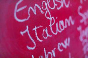 Fremdsprachen: das Wort "Italian" mit Kreide in einer Liste auf einer pinkfarbenen Tafel geschrieben
