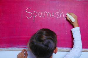 Fremdsprachen: das Wort "Spanish" wird mit Kreide auf einer pinkfarbenen Tafel geschrieben