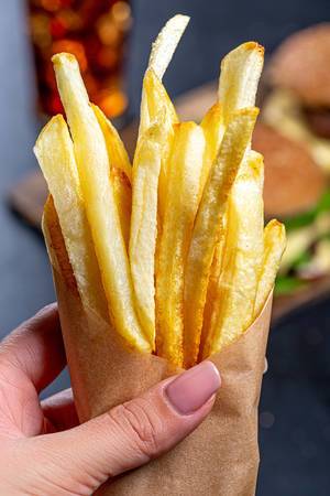 French fries in a paper wrapper in a woman