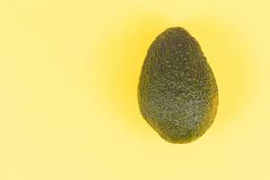 Fresh Avocado above yellow background with copy space