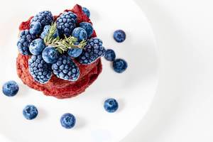 Fresh blueberry and mulberry berries on beet pancakes, top view (Flip 2019)