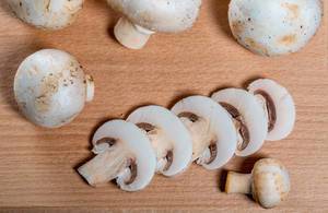 Fresh champignon mushrooms on wooden background.