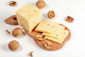 Fresh cheese with walnuts on wooden kitchen Board on white background