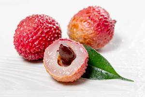 Fresh cut lychee fruit with big nut and whole lychees on white background (Flip 2019)