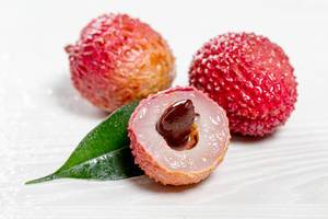 Fresh cut lychee fruit with big nut and whole lychees on white background