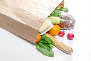 Fresh food on a white background in an open paper bag