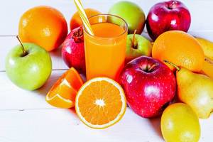 Fresh fruit: Oranges, apples, pears, lemon, pomegranate and fruit juice in a glass on white wooden background