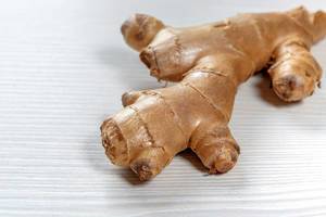 Fresh ginger root on white wooden background