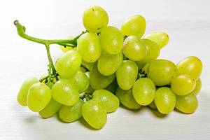 Fresh green grapes on white wooden background
