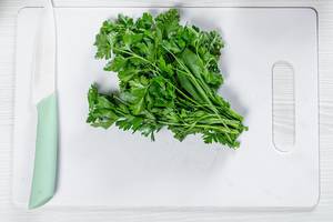 Fresh green parsley with a ceramic knife on a white kitchen Board (Flip 2019)