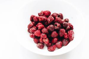 Fresh raspberries in a white plate on white background. Close up