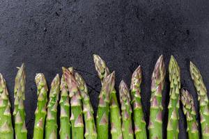 Fresh raw green asparagus on black background