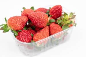 Fresh Raw Strawberries in the plastic box above white background (Flip 2020)