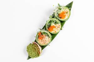 Fresh rolls with cucumber, avocado, crab, arugula and micro-greens on a large green leaf. Top view