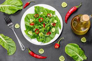Fresh Romaine lettuce salad with cucumber and chili pepper ingredients on black background (Flip 2019)