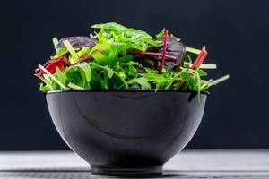 Fresh salad with a mixture of different lettuce and arugula in a black bowl