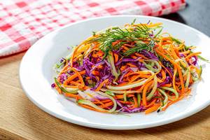 Fresh salad with carrots, cucumber and purple cabbage on a white plate (Flip 2019)