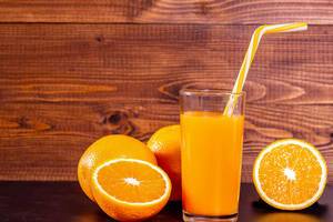 Fresh squeezed natural orange juice with oranges on wooden background