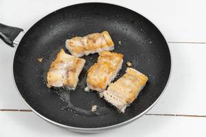 Fried Alaska Pollock fish on the frying pan (Flip 2020)