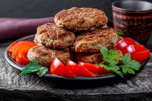 Fried cutlets with tomatoes and parsley on a wooden background