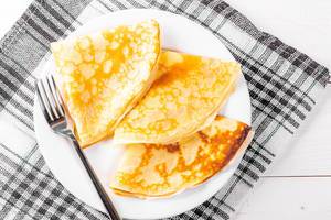 Fried pancakes on a plate with a fork and a kitchen towel
