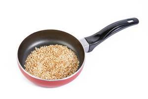 Fried Sesame in the frying pan isolated above white background