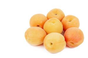Frische Aprikosen liegen im Kreis vor einem weißen Hinterrund