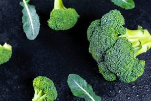 Frischer Broccoli auf schwarzem Hintergrund mit Wassertropfen