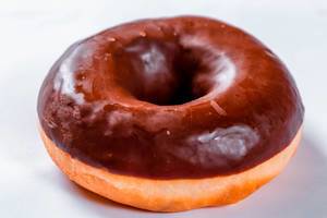 Frischer Donut mit Schokoladenglasur vor weißem Hintergrund