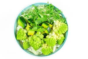 Frischer grüner Salat mit Romanesco Kohl, Avocado, Petersilie und Wasserkresse in einer Schale auf weißem Hintergrund fotografiert