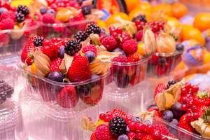 Frischer Obstsalat mit Erdbeeren, Johannisbeeren, Blaubeeren und Brombeeren in Plastikverpackungen, werden in den Markthallen Mercat de la Boquerìa in Barcelona, Spanien, verkauft
