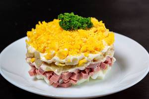 Frischer Salat aus Schinken, Kartoffeln, Eiern und Mayonnaise auf weißem Teller