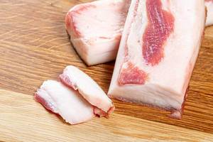 Frisches Schweinefleisch-Fett, geschnitten auf einem hölzernen Küchenbrettchen