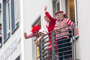 From the balconies of Cologne, people in traditional red and white costumes (red-white are the colours of the city) cheer and greet as the Rose Monday parade passes by