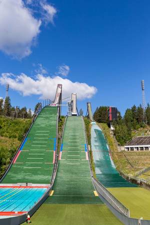 Front view of the ski jump Salpausselkä, in front of a cloudy sky, with inbuilt outdoor swimming pool in Lahti, Finland