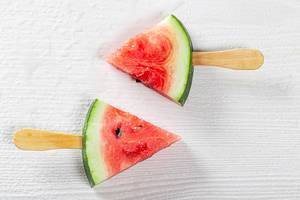 Fruchteis-Konzeptbild, mit kleinen Wassermelonenstücken auf Holzspießen