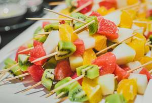 Fruchtsalat auf Spießen bestehend aus Kiwi, Orange und Apfel